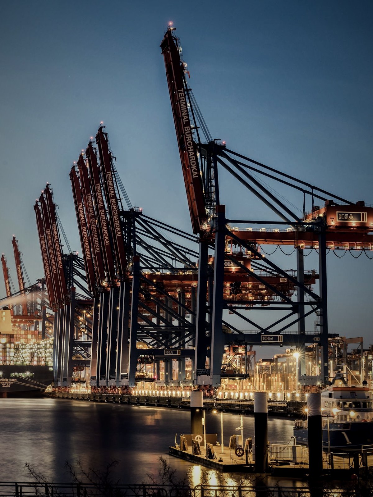 A container terminal at dusk, gantry cranes loading a cargo ship — the cross-border trade Yodo is built around.