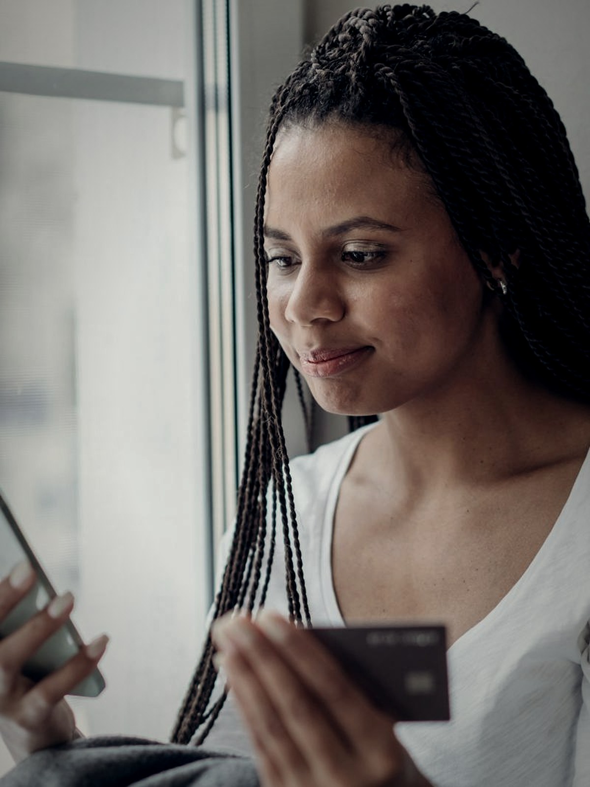 A woman checking her phone, card in hand — the social-first wallet Yodo Pay is building.